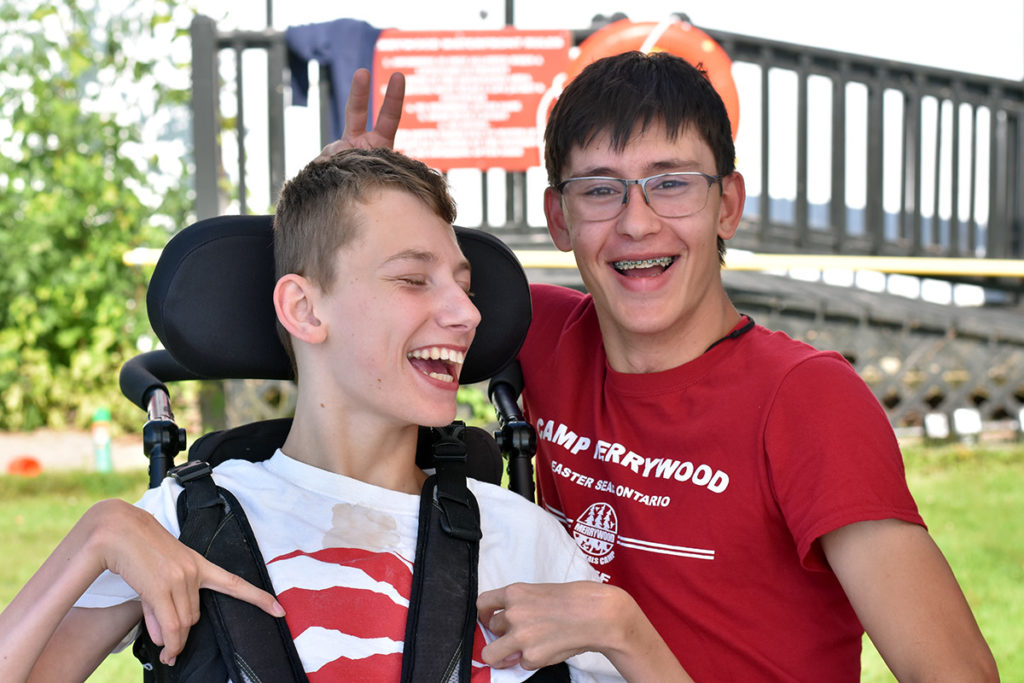 A boy in wheel chair and another boy smile