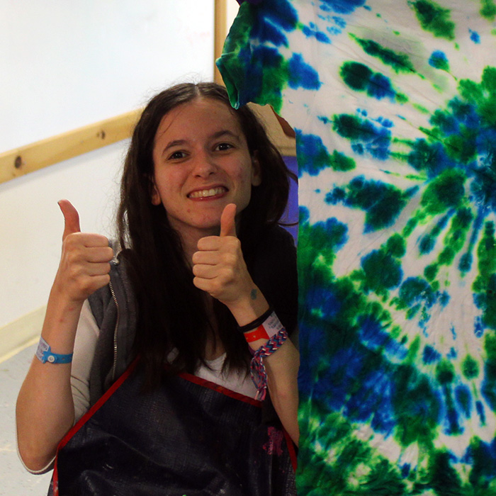 A girl gives a thumbs up beside a tie-dyed t-shirt.