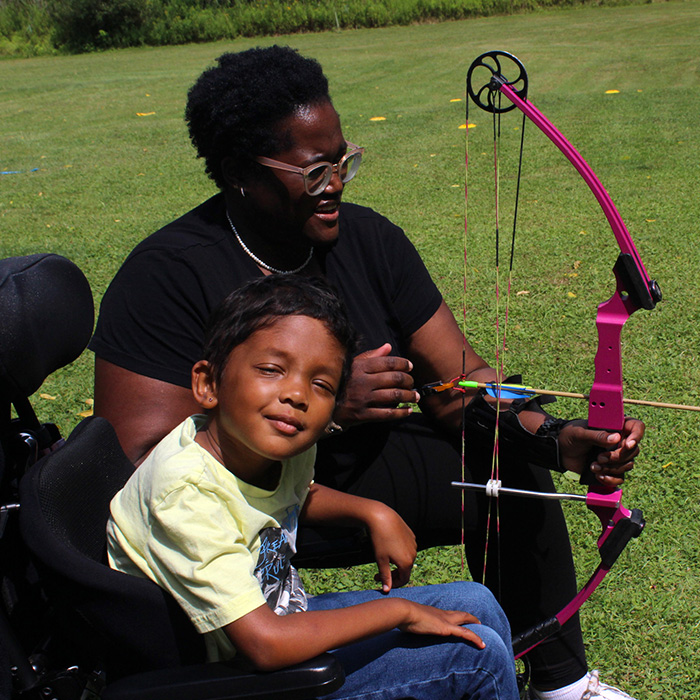 A boy and his parent practice archery.