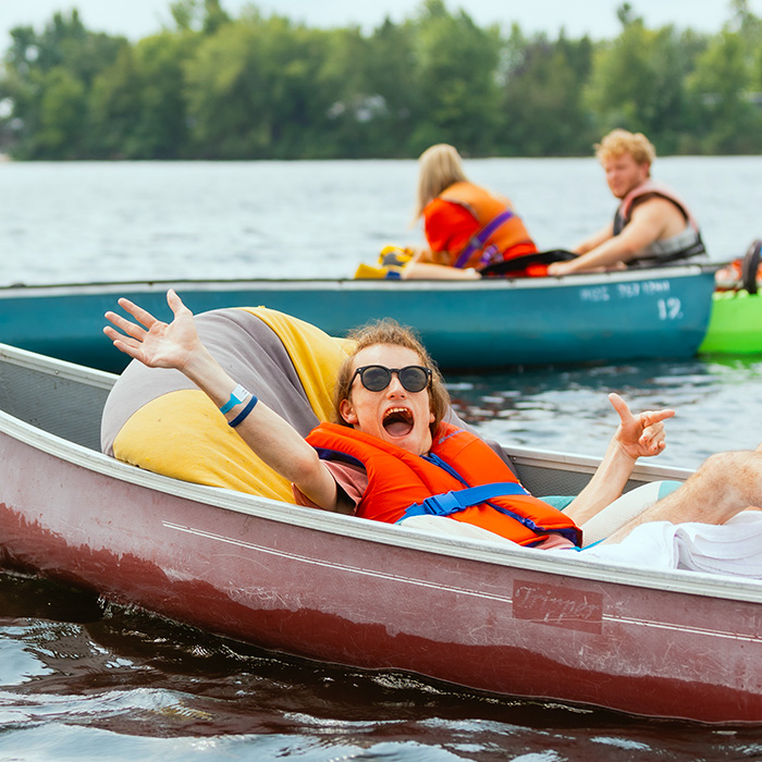 A boy waves from a canoe.
