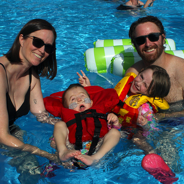 A family smiles while swimming in the pool.