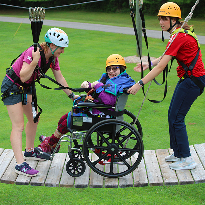 A girl smiles from her wheelchair atop of the high-ropes course.
