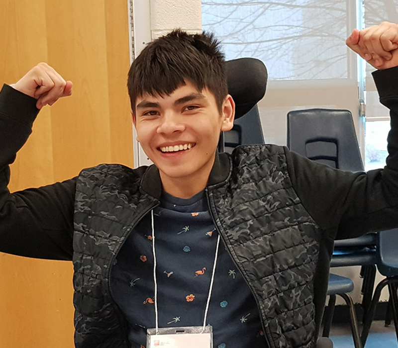 A boy at the pathways to success seminar smiles with his hands raised.