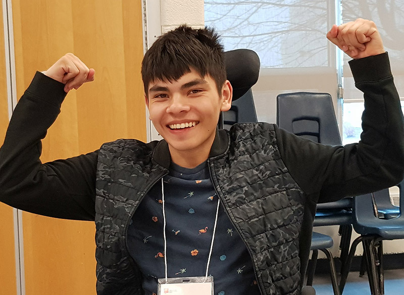 A boy at the pathways to success seminar smiles with his hands raised.