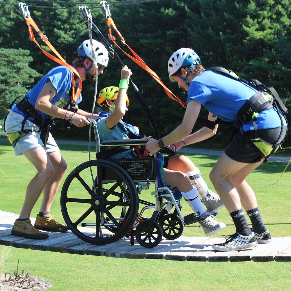 A camper and councilors on the high ropes course.